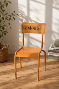 Chaise d'écolier vintage relookée avec de la peinture à la craie Annie Sloan, couleur orange lumineux, avec dossier en bois naturel avec inscriptions "JAMAIS!!" et "SILENCE" en lettres noires style industriel.