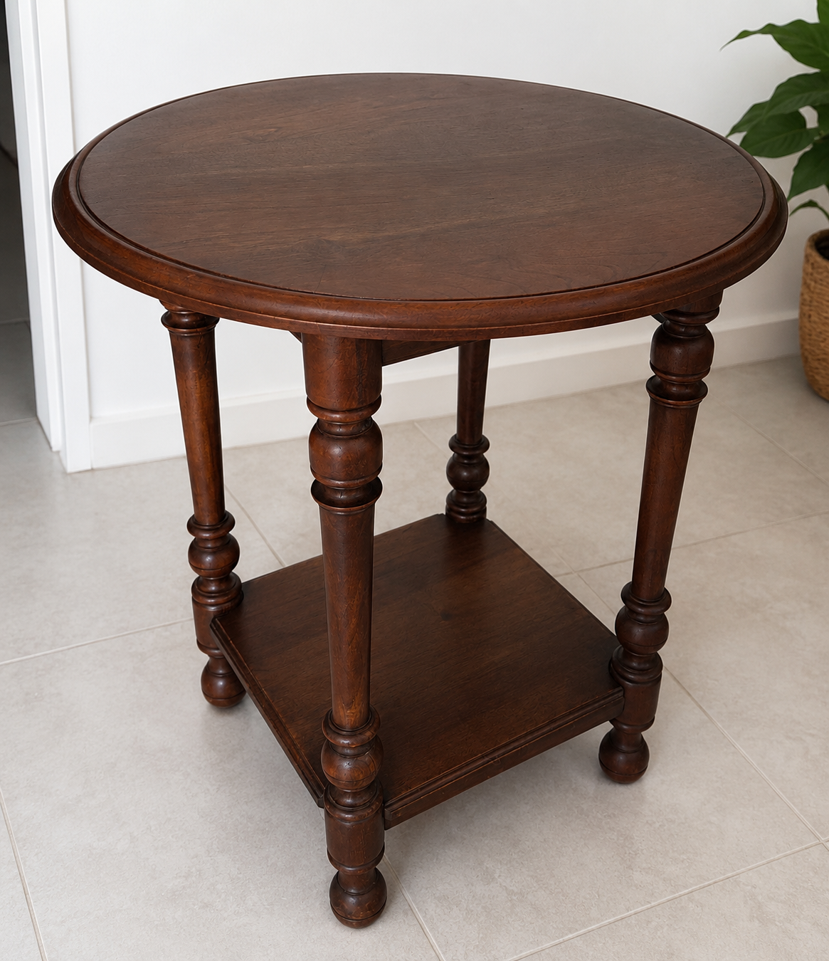 Table d’appoint ronde vintage en bois foncé avant relooking. Ce guéridon à deux niveaux possède un plateau circulaire, une tablette inférieure et des pieds tournés, dans un style classique intemporel.