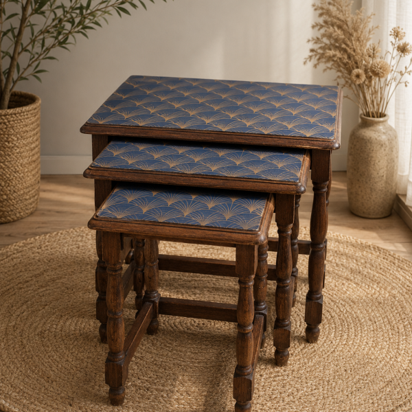 Ensemble de trois tables gigognes vintage en bois foncé, utilisées comme tables d’appoint. Les plateaux sont recouverts d’un motif Art déco bleu et doré, sous la forme d'un film plastifié. Photo prise avant relooking du mobilier.